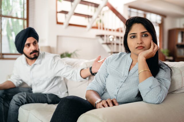 A woman looking away from a man while he reaches out to her