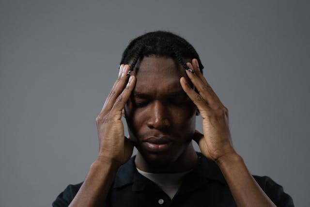 Man holding his hands on his head with his eyes closed