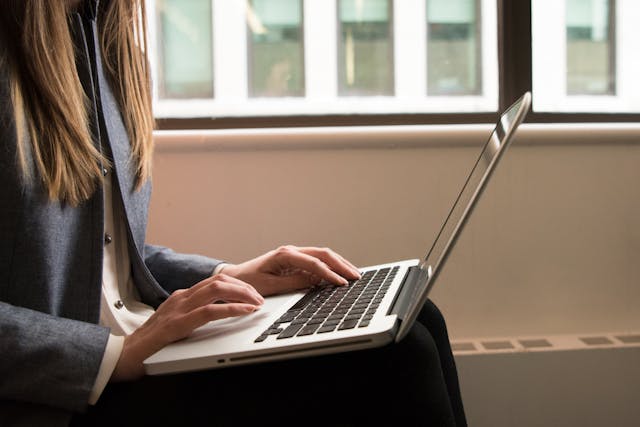 Closeup image of a woman typing on a laptop 